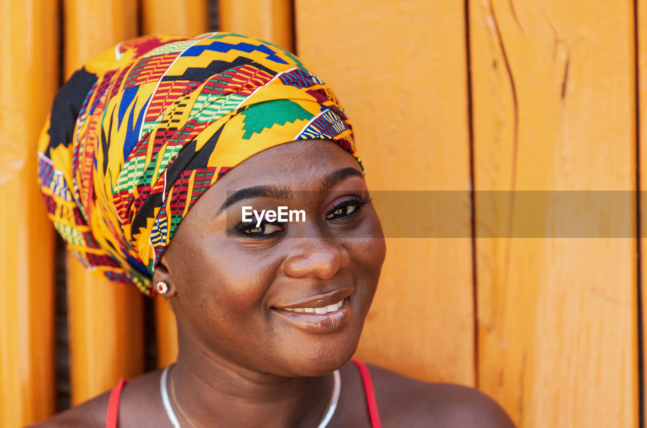  woman with a hopeful happy smile and traditional headdress  in the tropical village of keta ghana,