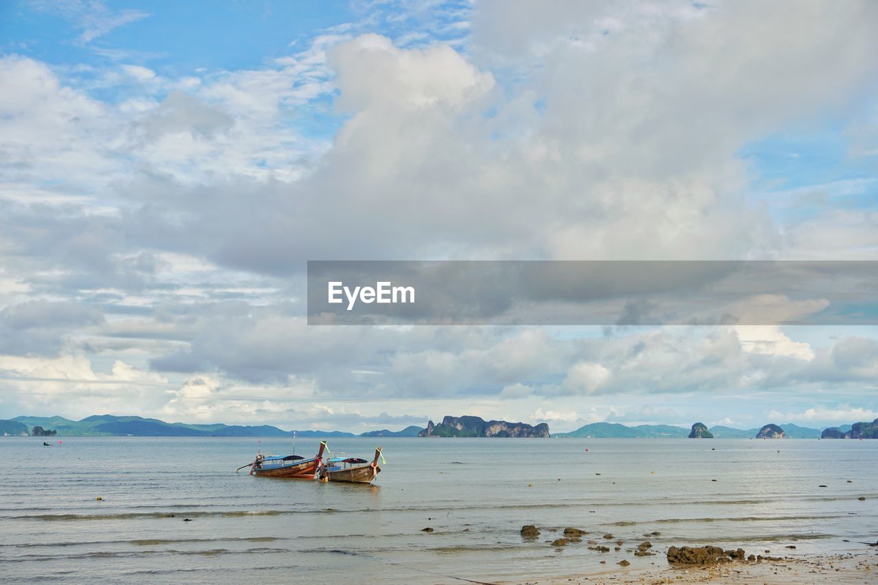 BOAT ON SEA SHORE AGAINST SKY