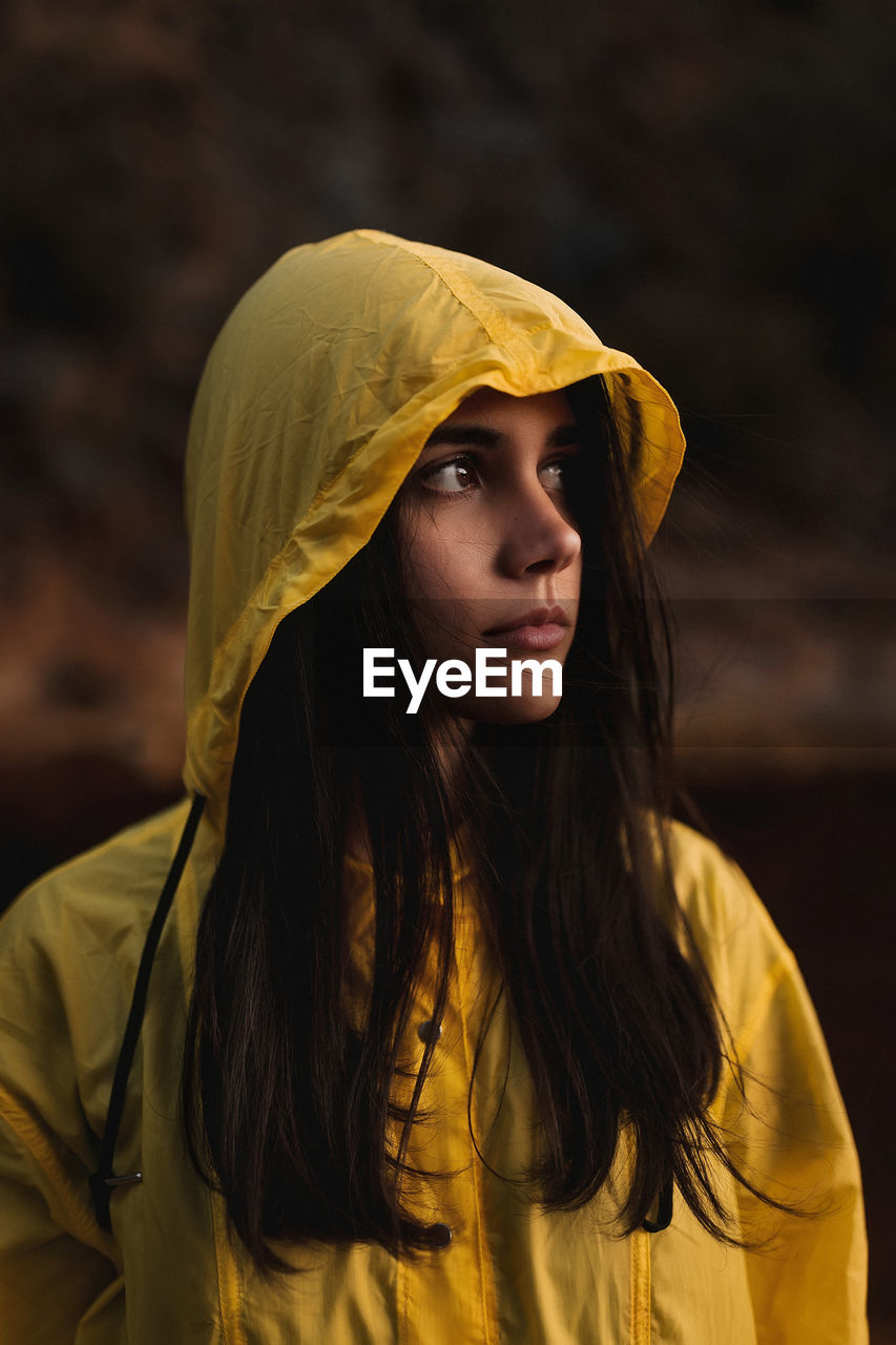 Young lady in yellow raincoat strolling in nature