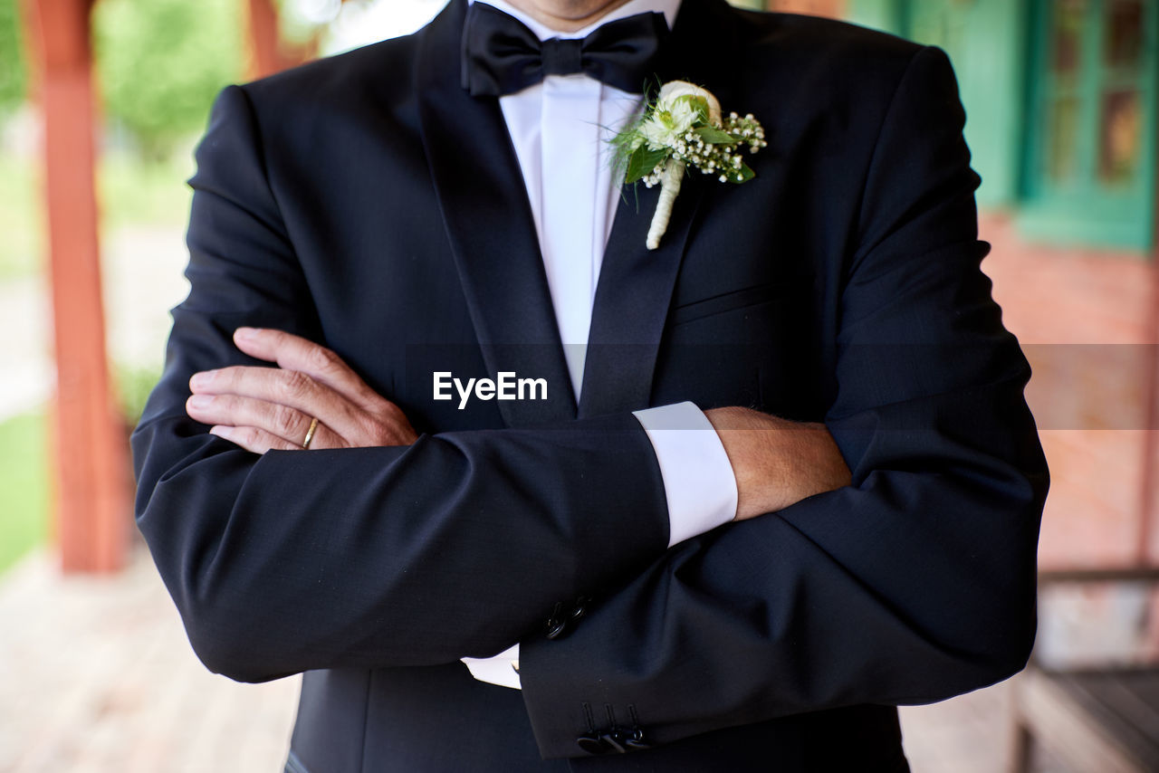 Midsection of bridegroom standing with arms crossed