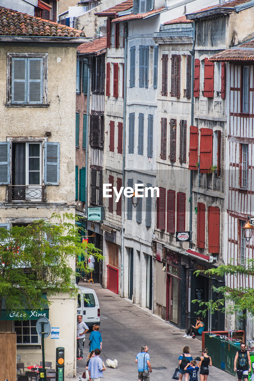 PEOPLE WALKING ON STREET BY BUILDINGS IN CITY