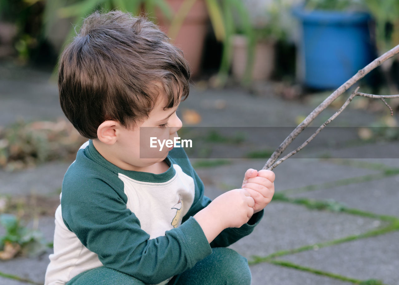 Boy playing with a stick in the garden