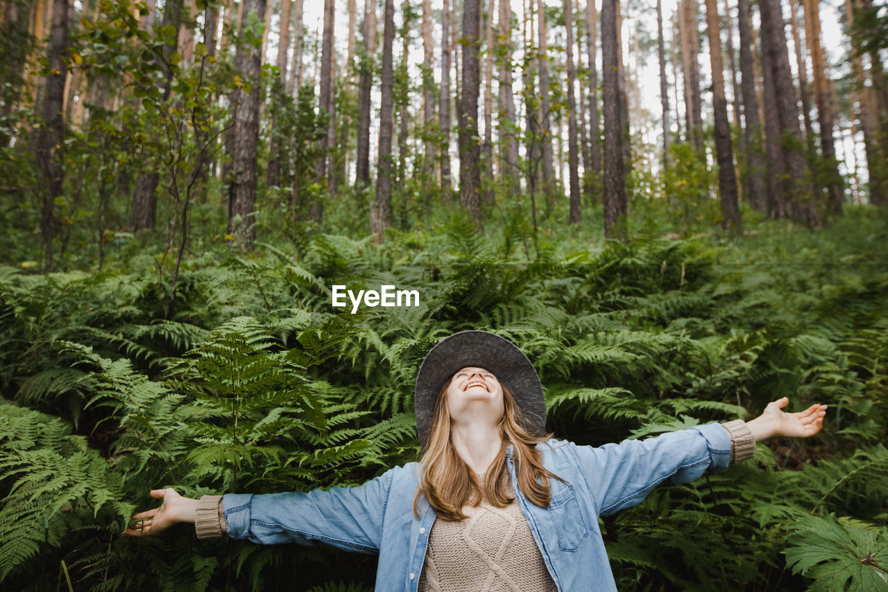 Cheerful woman enjoying freedom in green forest