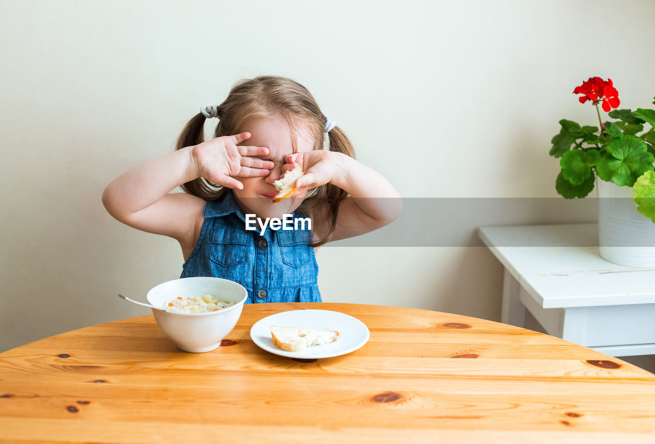 Cute girl eating food at table