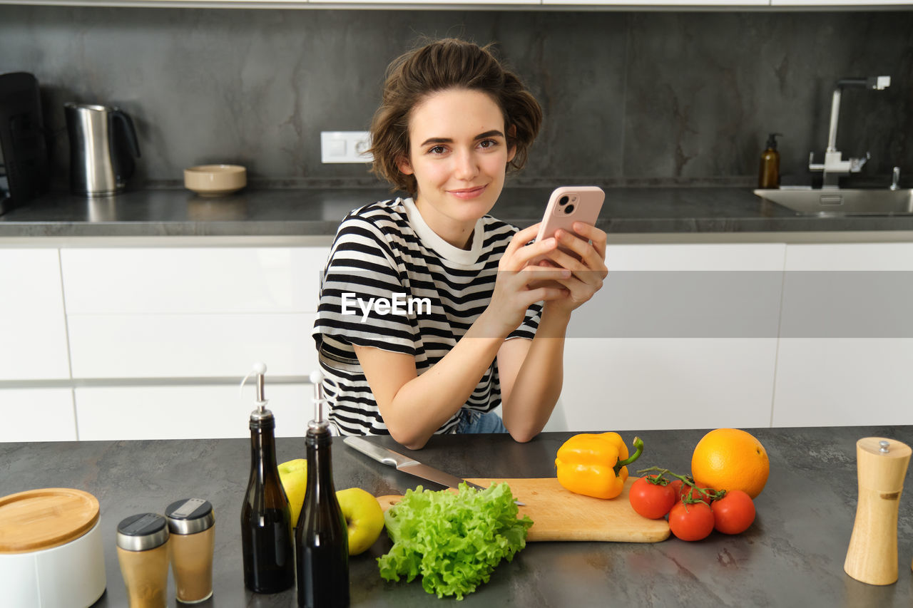young woman using mobile phone while sitting on table