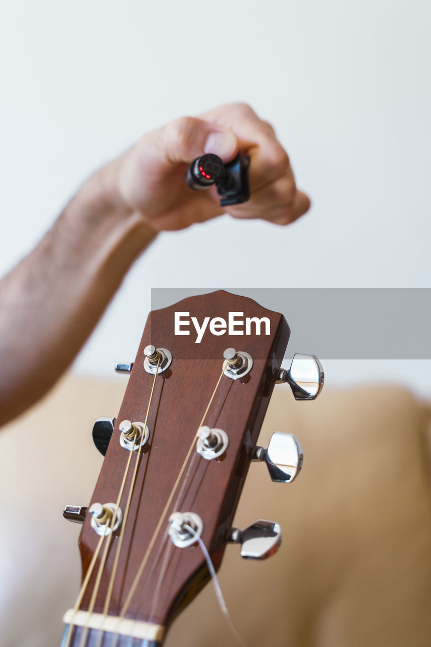 Cropped hand of man preparing guitar in home