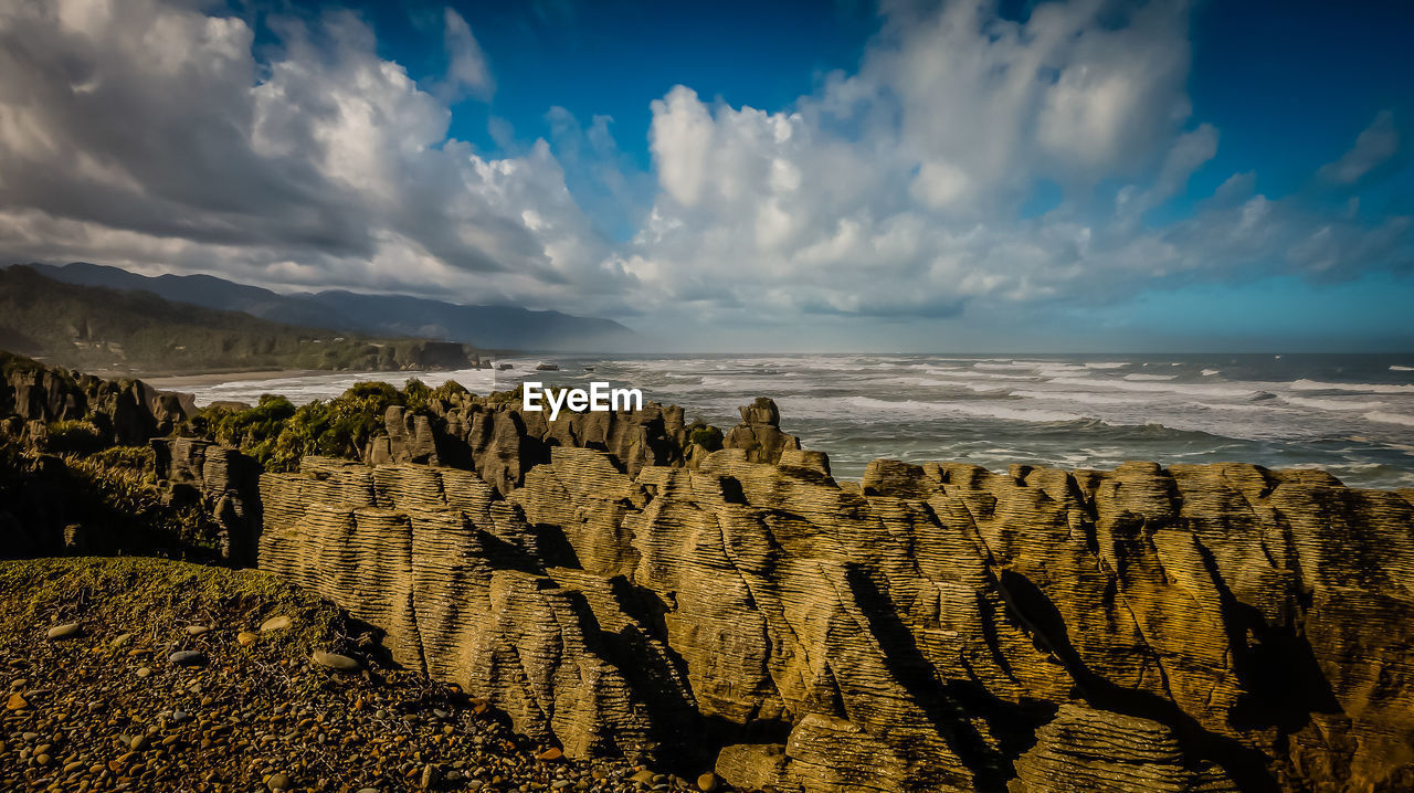 Scenic view of pancake rocks by sea against sky