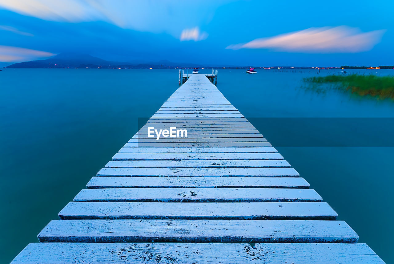 Pier over lake against blue sky