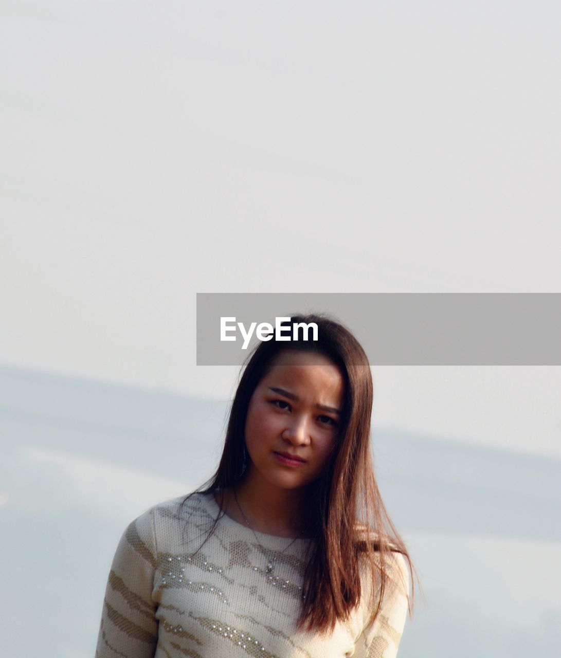 Portrait of young woman against sky