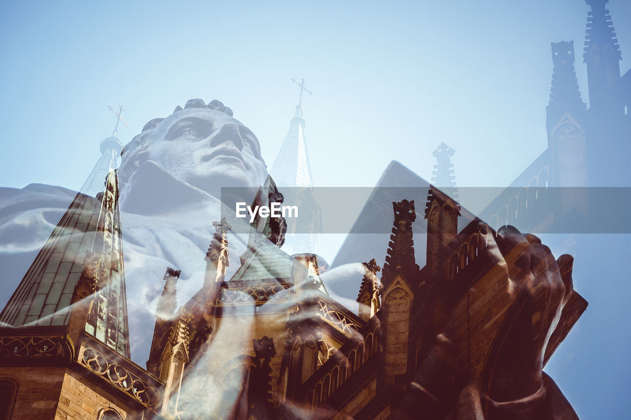 Double exposure of statue and church against sky