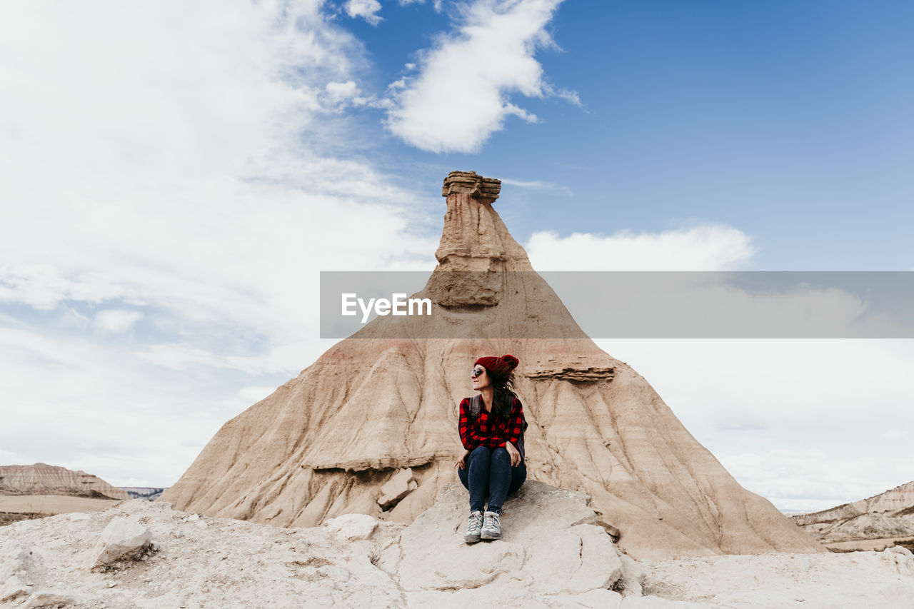 Spain, navarre, female tourist sitting in front of sandstone rock formation in bardenas reales