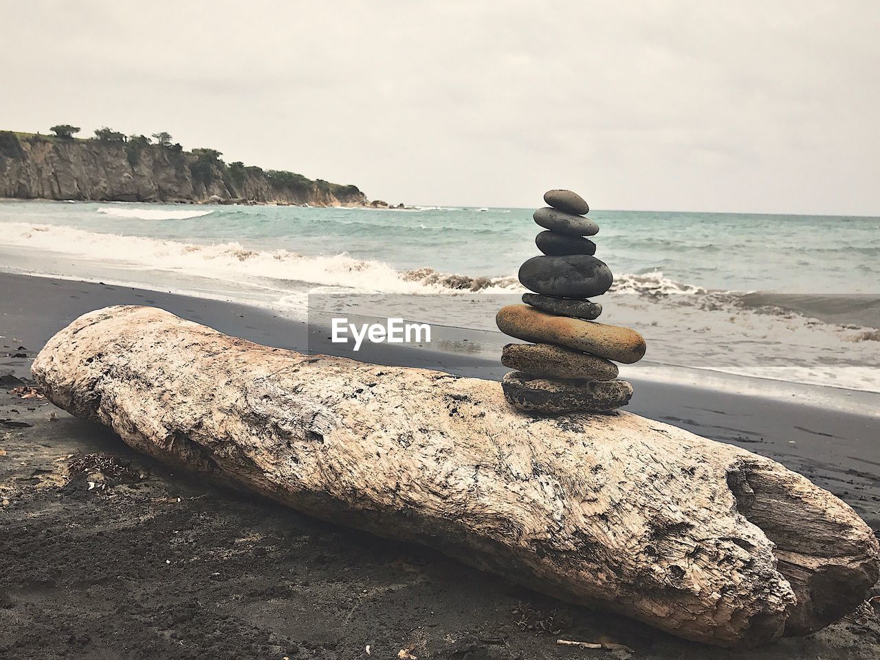 STACK OF PEBBLES ON SAND AT BEACH