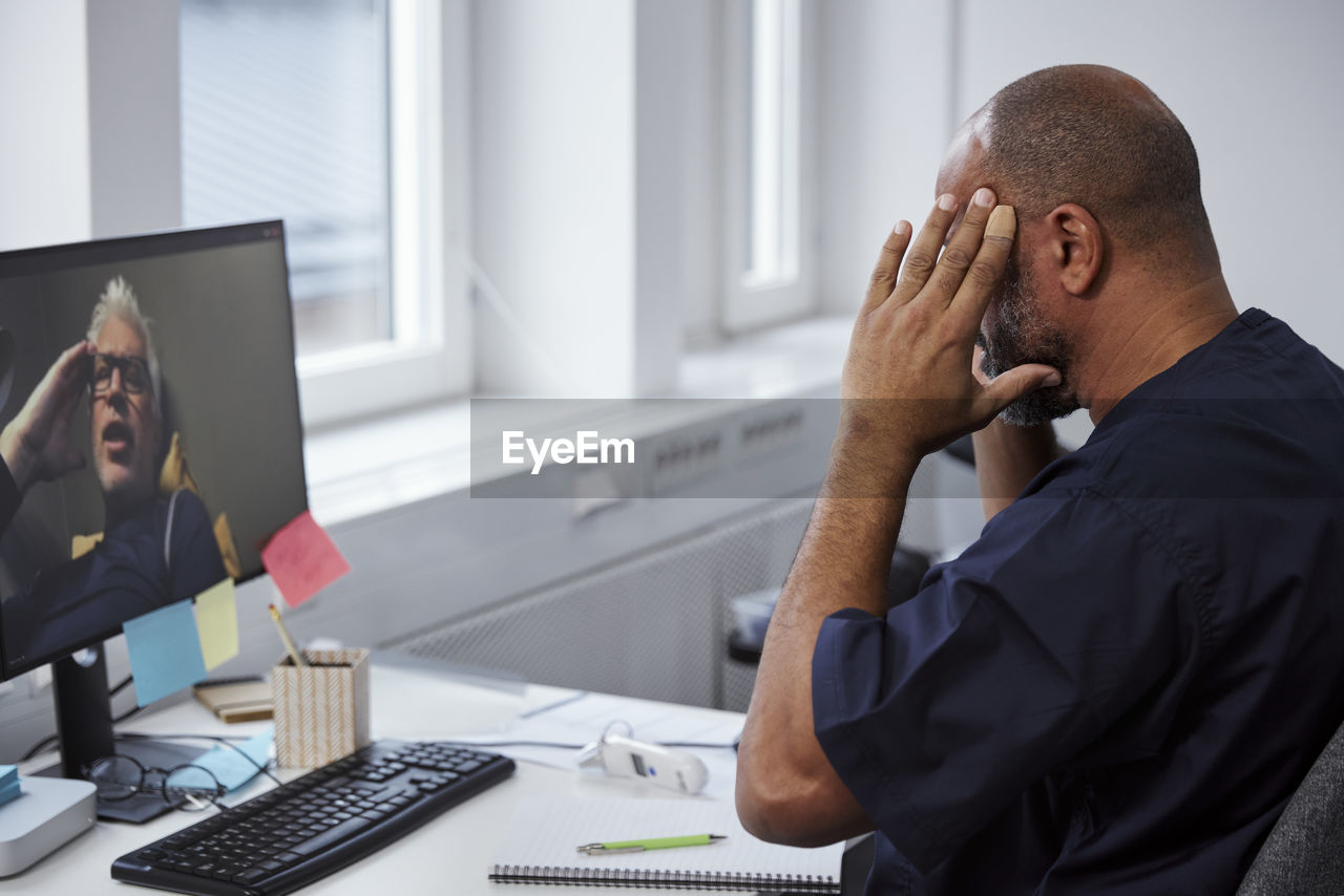 Male doctor having online consultation with senior patient