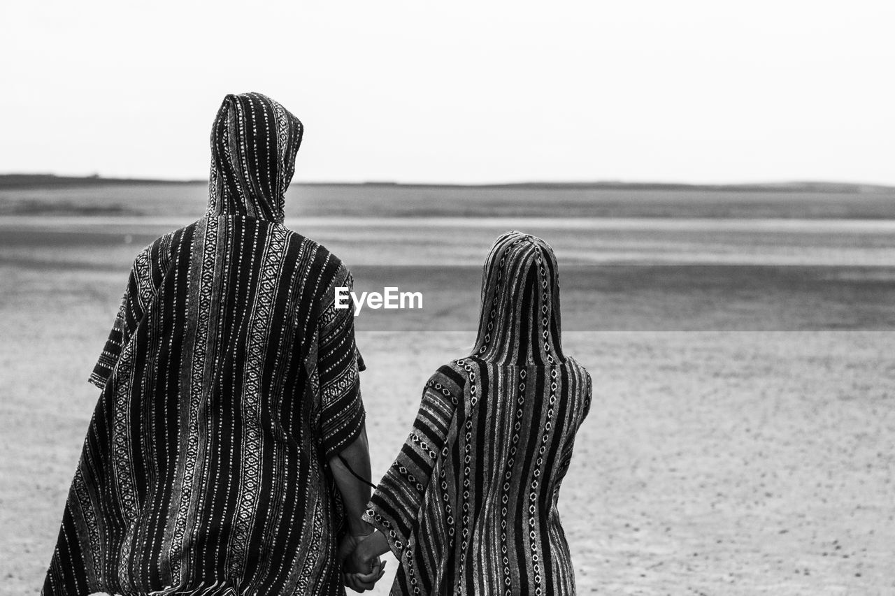 Rear view of woman and girl on field against sky