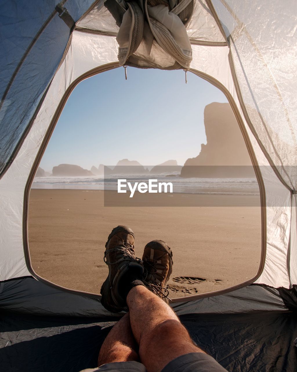 Low section of man sitting in tent at beach