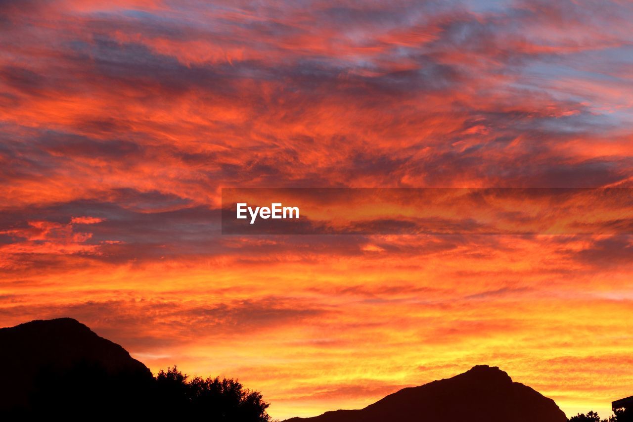 LOW ANGLE VIEW OF DRAMATIC SKY OVER SILHOUETTE MOUNTAINS