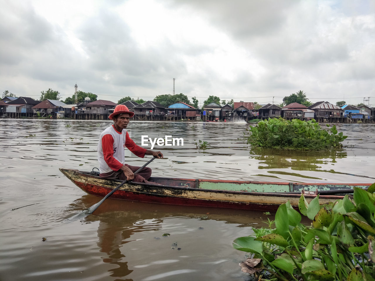 Man sitting on boat in river against sky