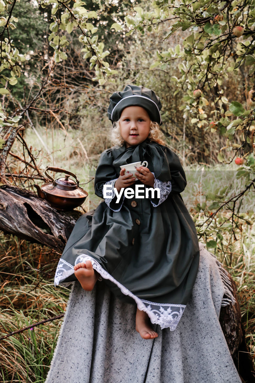 Full length of girl sitting on branch