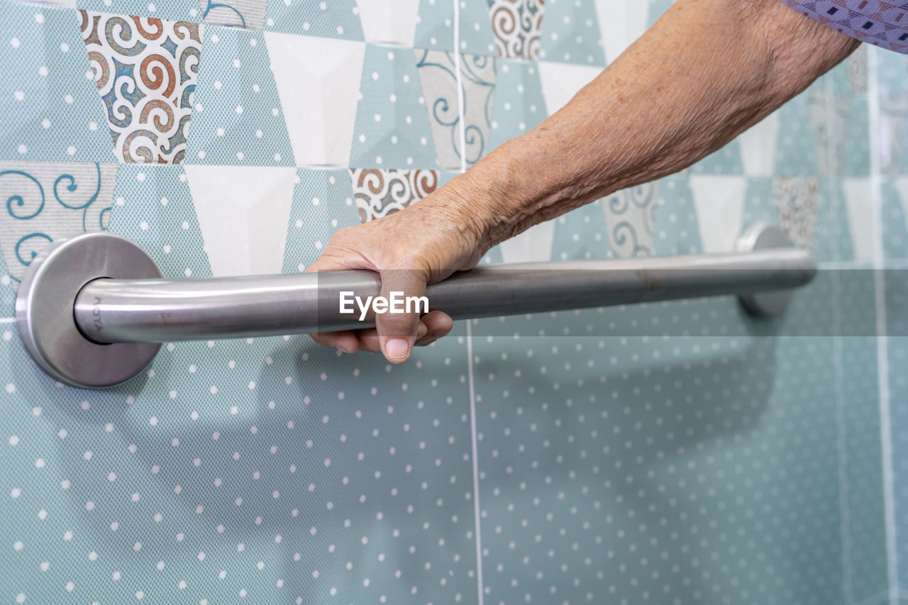 Cropped hand of senior woman holding handrail