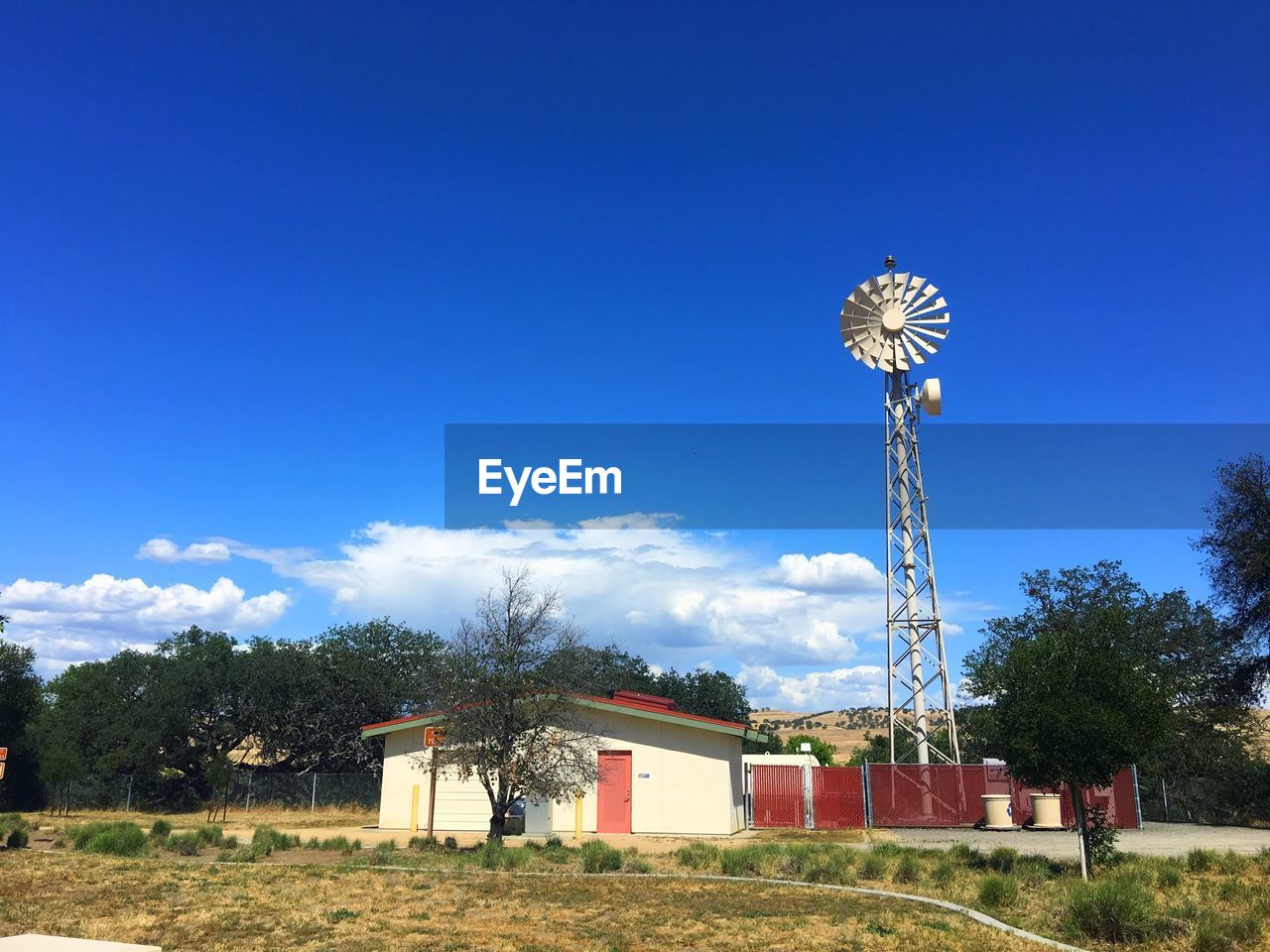 House by american-style windmill against blue sky