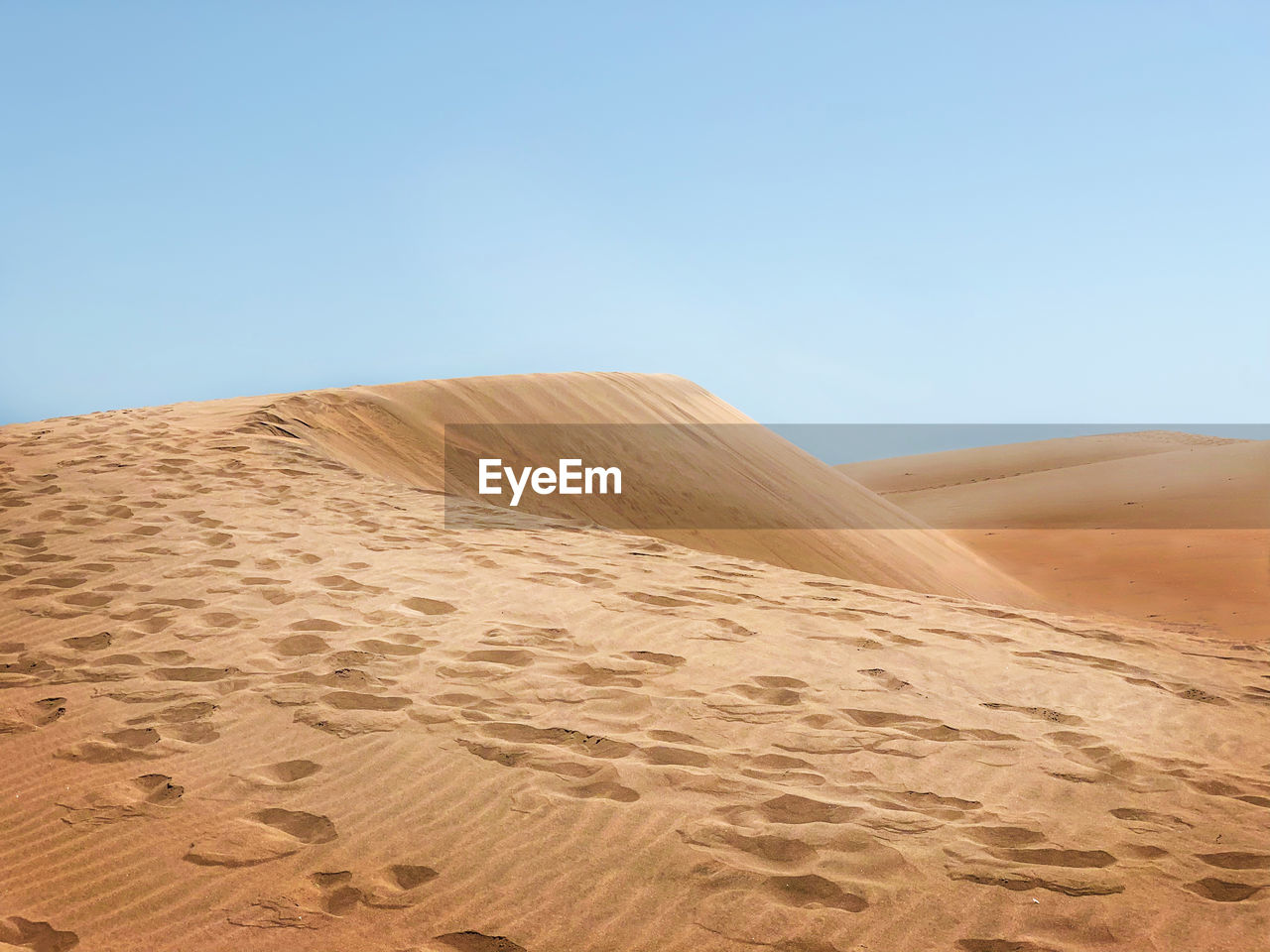 Sand dunes in desert against clear sky