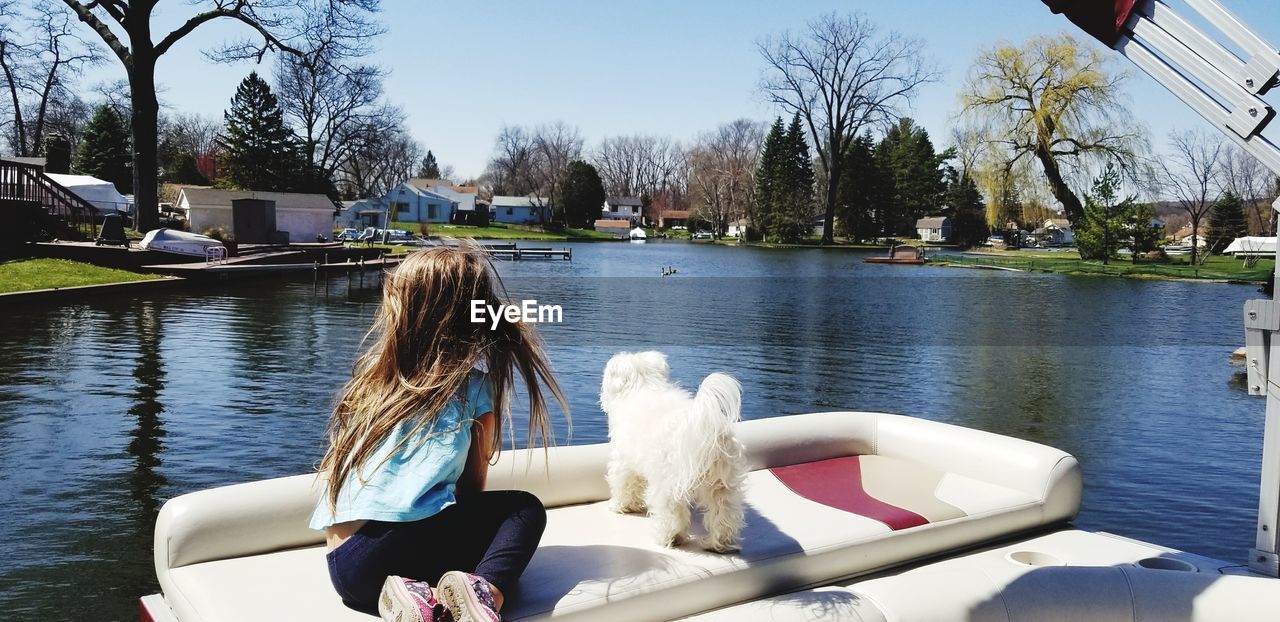 Rear view of girl sitting in boat at lake