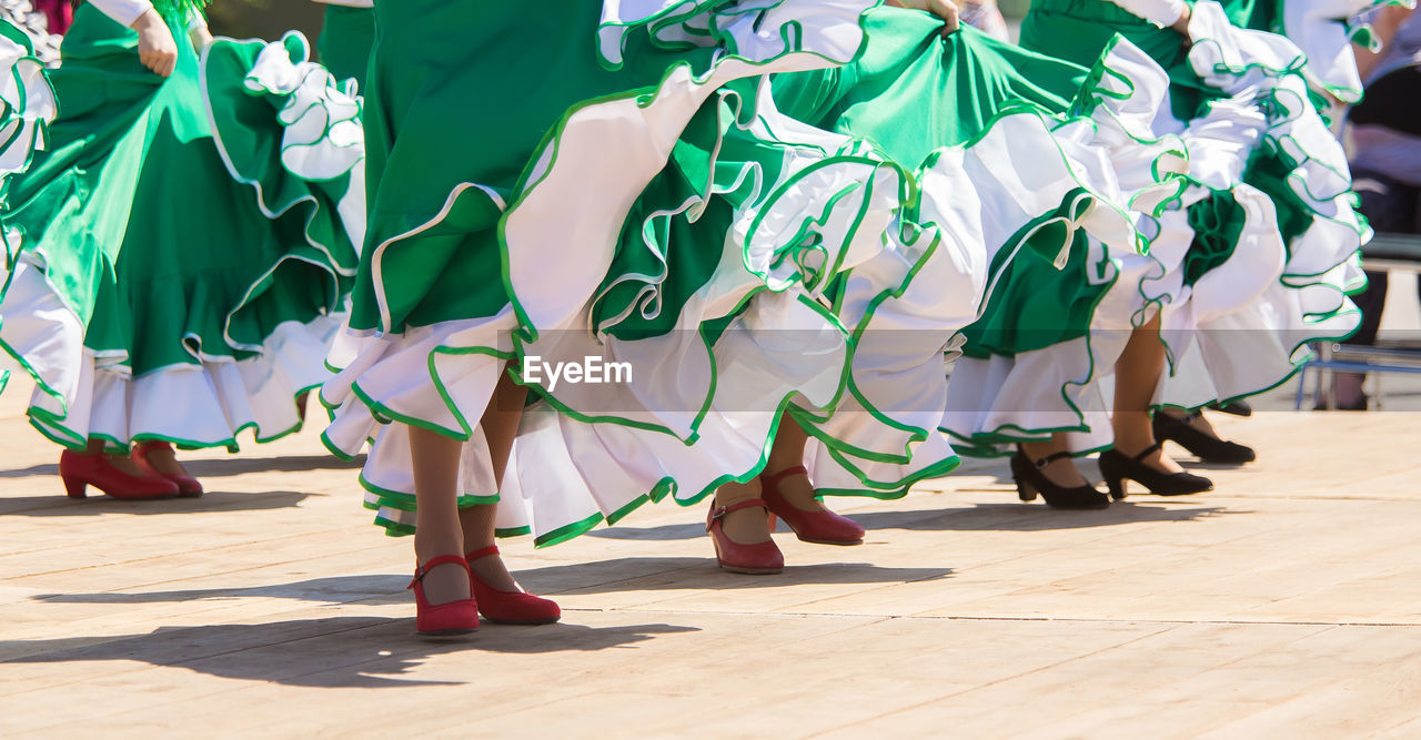 Low section of women dancing on footpath during sunny day