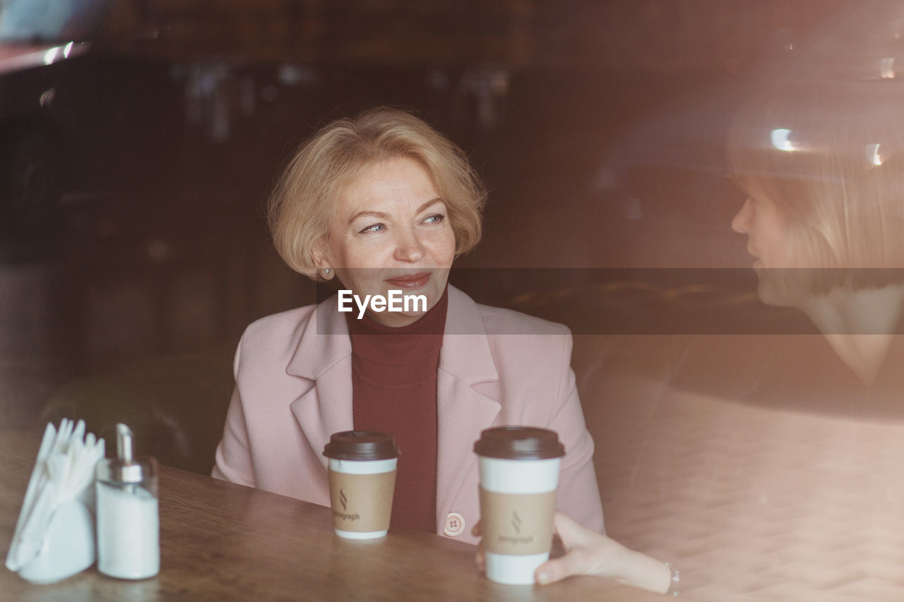 Mother and daughter talking while sitting in cafe