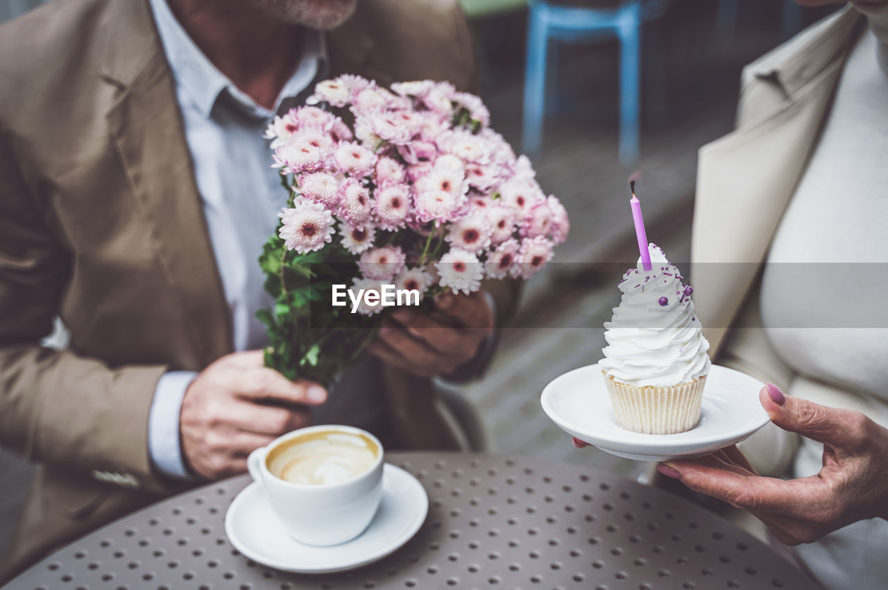 CROPPED IMAGE OF HAND HOLDING COFFEE CUP ON TABLE