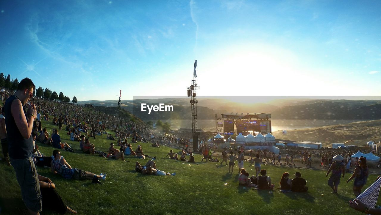 People relaxing at music concert against sky