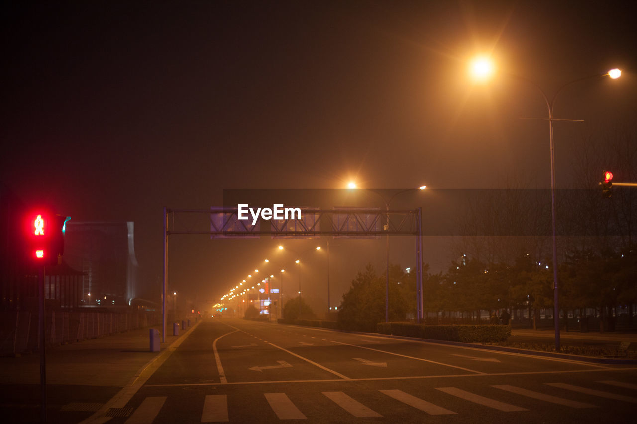 Empty road along street lights at night