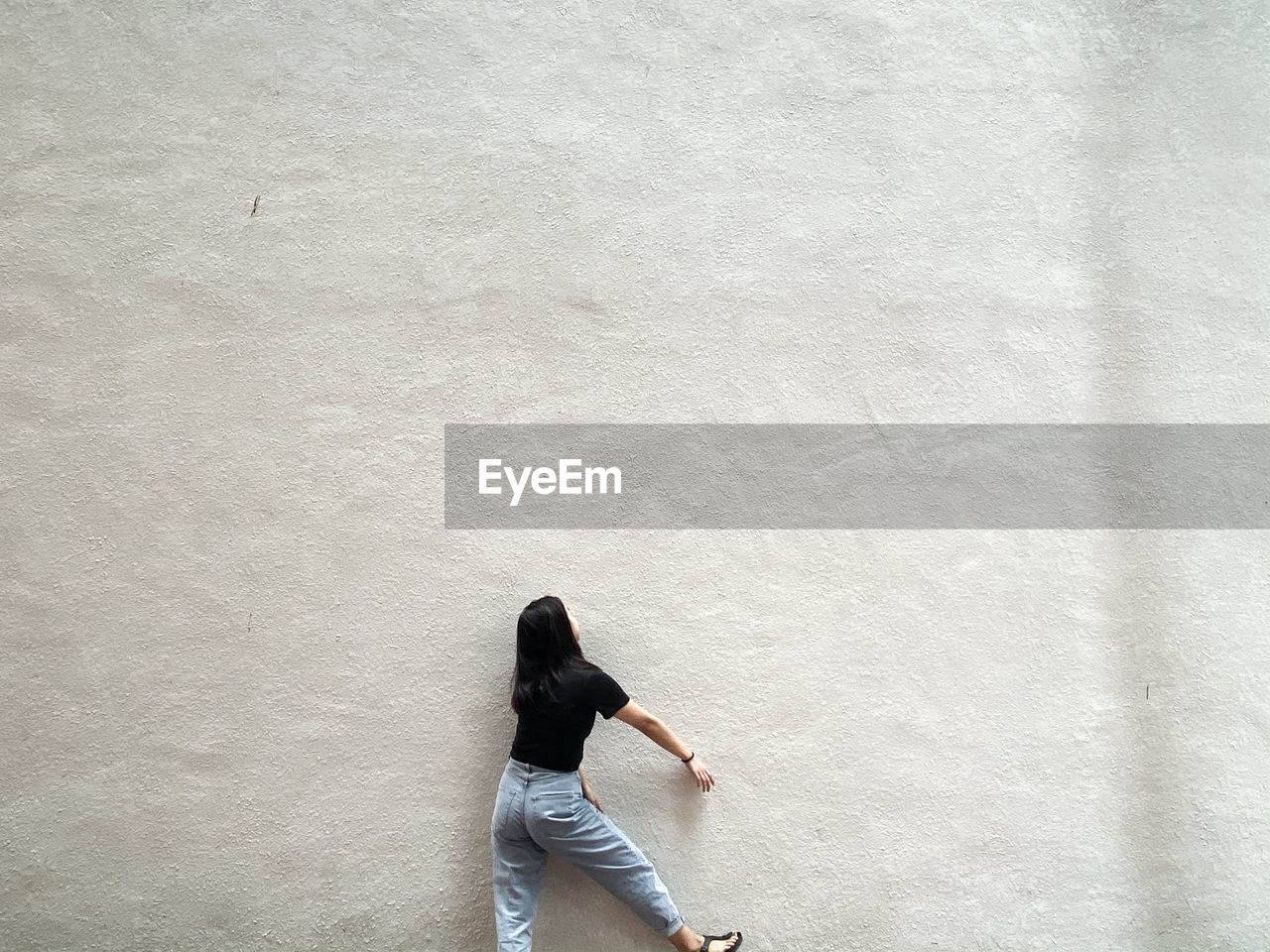 Rear view of woman standing against wall