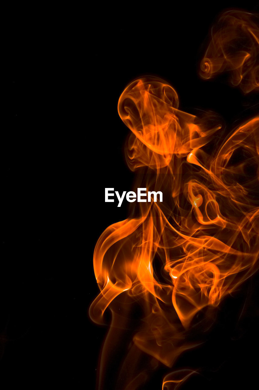 Close-up of orange smoke against black background