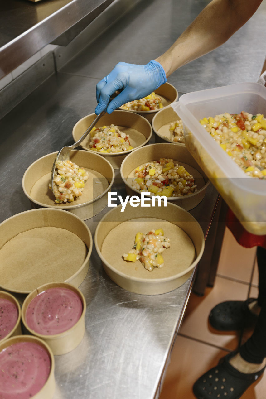 Cook preparing vegetable salads and homemade ice creams to take away. 