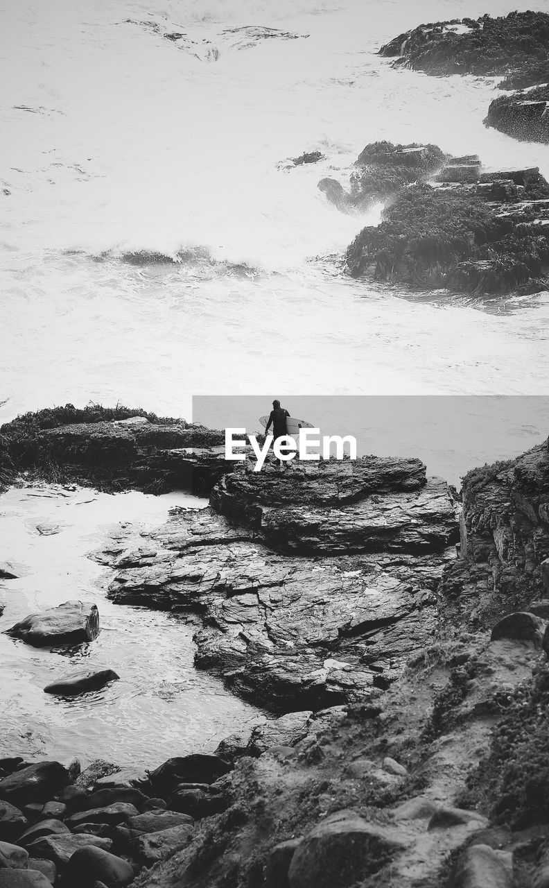 High angle view of man with surfboard standing at beach