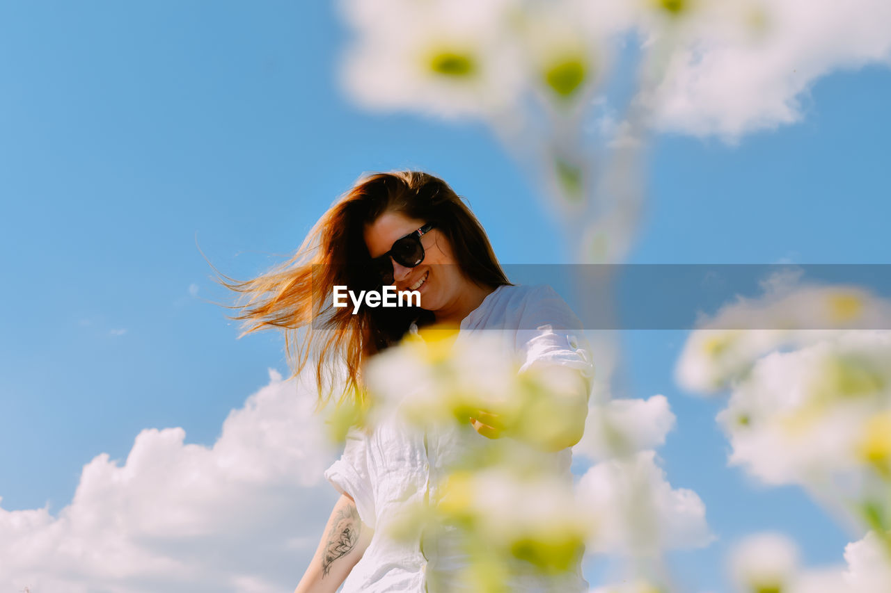 Young woman standing against sky