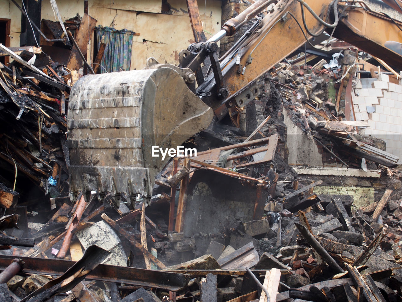 A hydraulic excavator machine working on a demolition site clearing debris