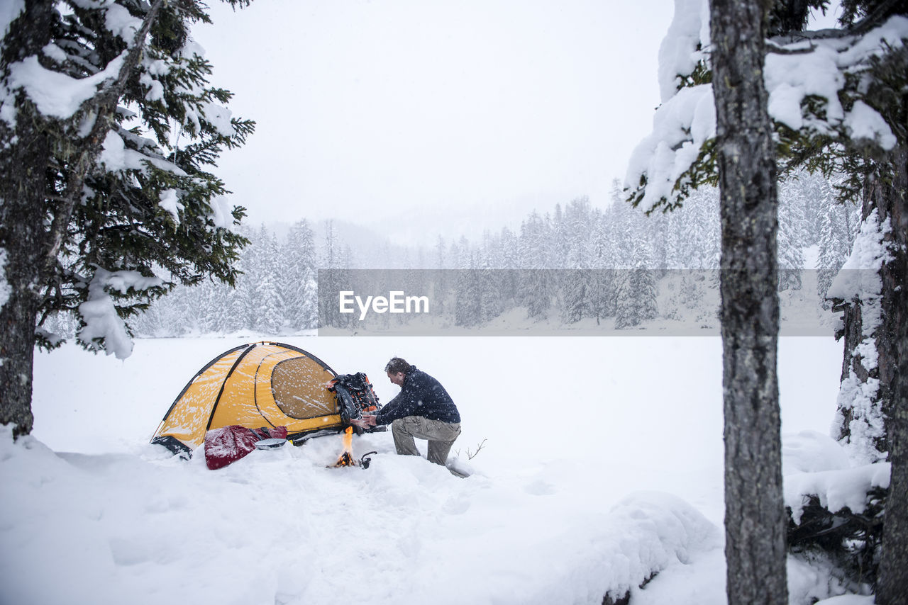 Senior man camping in snow-covered landscape