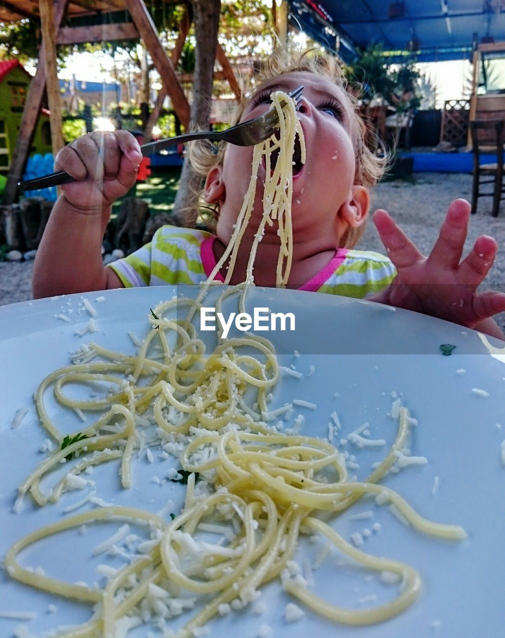 Close-up of child eating spaghetti in plate at park