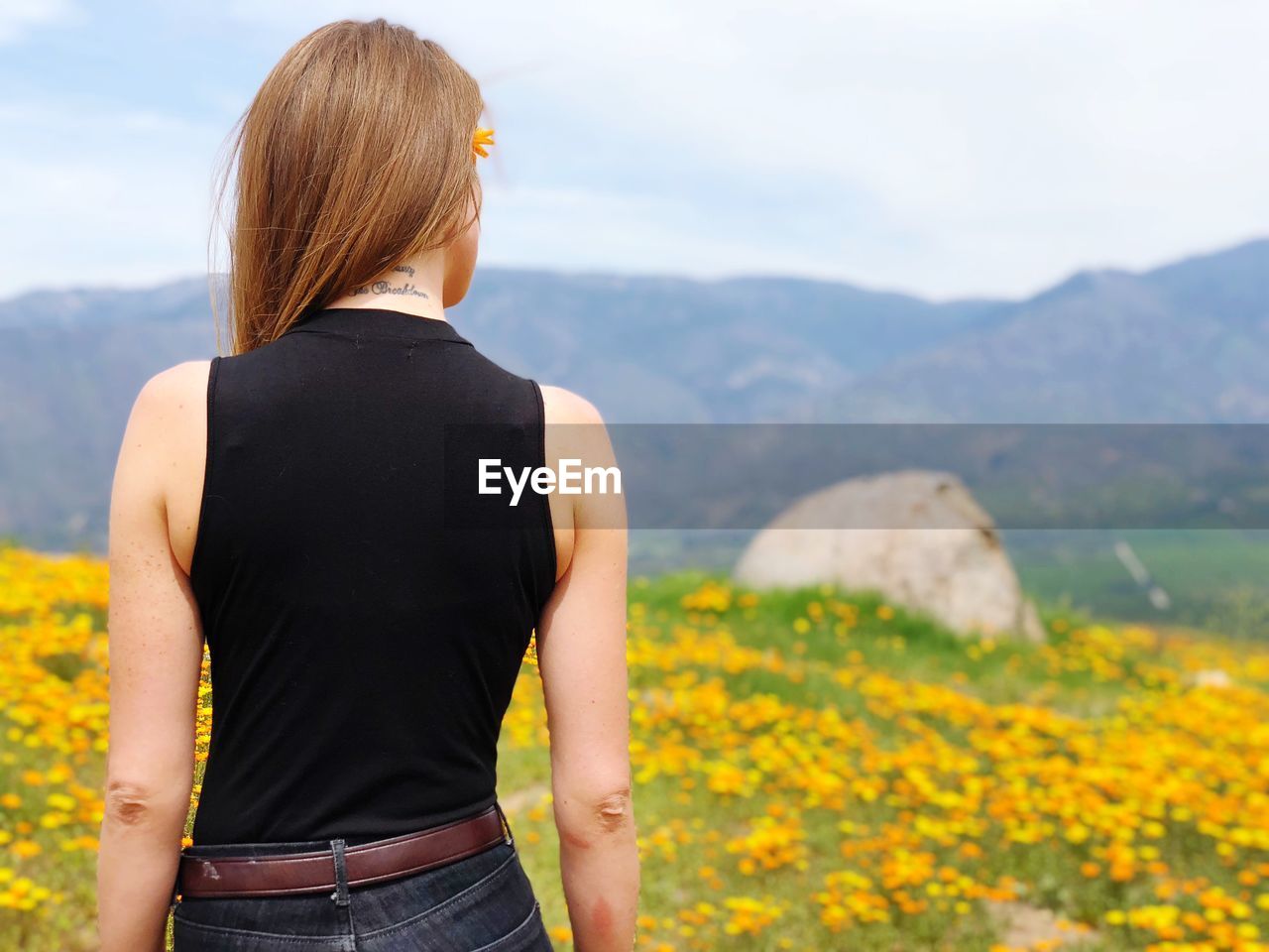 Rear view of woman standing on mountain against sky