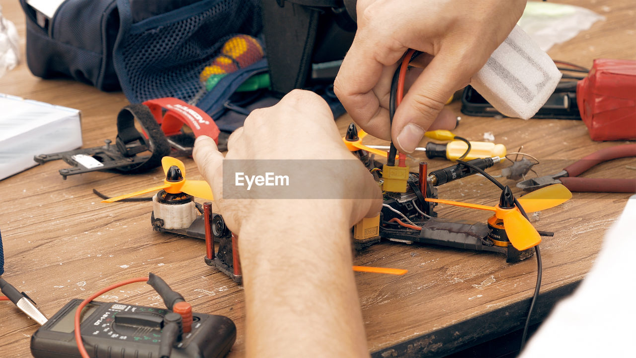 Cropped hands of man repairing quadcopter at workshop