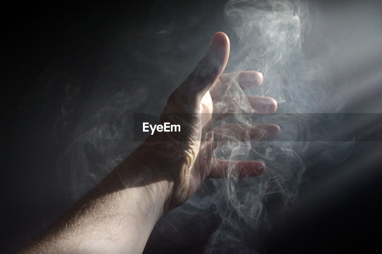 Close-up of human hand in smoke