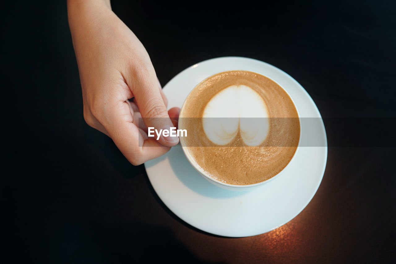 Cropped hand holding coffee cup on table