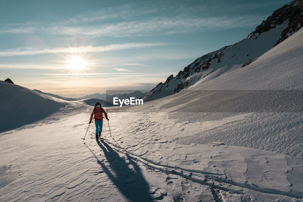 Man skitouring on a glacier with a sunrise background