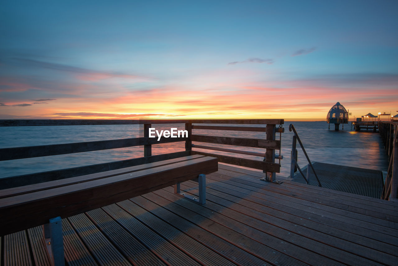 Pier on sea against sky during sunset