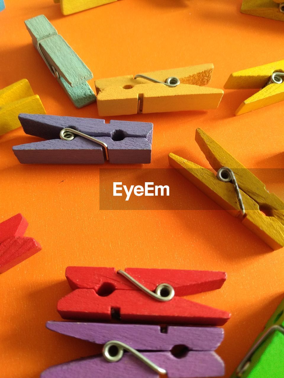 High angle view of colorful wooden clothespins on orange background