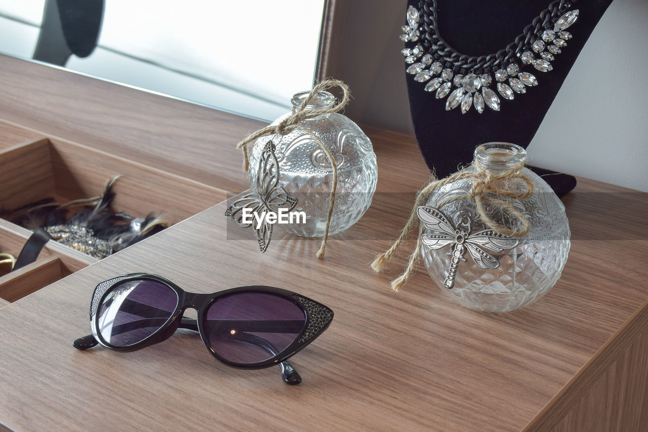 HIGH ANGLE VIEW OF SUNGLASSES WITH GLASS ON TABLE