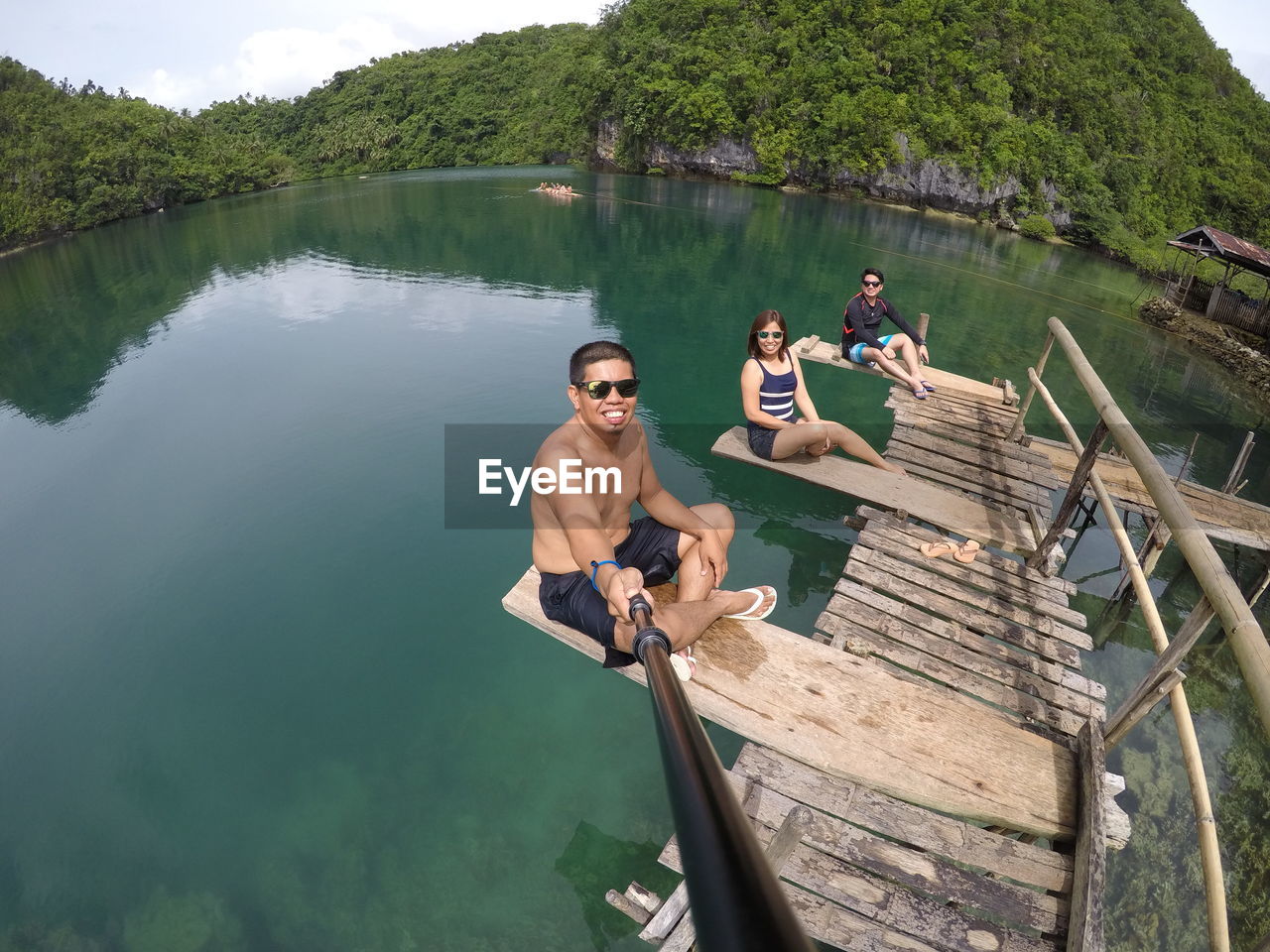 High angle portrait of friends sitting on pier over lake