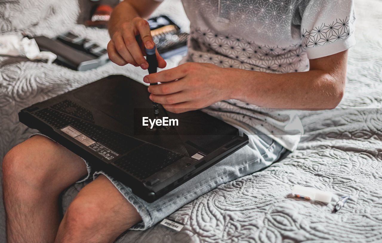 A young man is changing the thermal paste on a laptop.