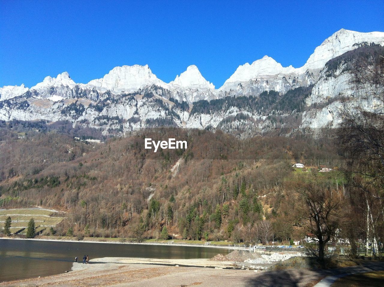 Scenic view of lake and snowcapped mountains against blue sky